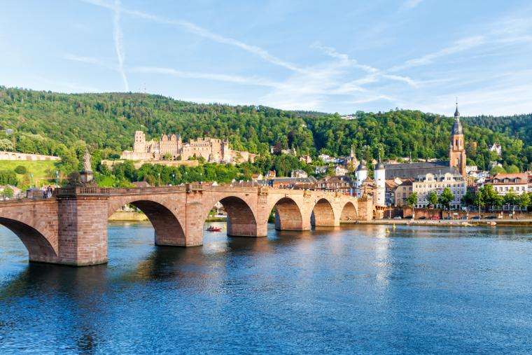 Heidelberg ukazuje historický zámek, Neckar a ikonický most ve starém městě pod modrou oblohou.