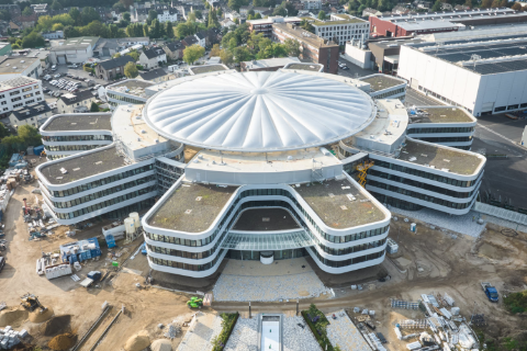 Střešní konstrukce propojuje dvorní budovy a poskytuje ochranu v areálu SMS, Mönchengladbach.