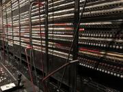 Starý telefonní systém s kabely a rozvaděči v serverové místnosti. Pozornost zaměřena na zastaralou technologii