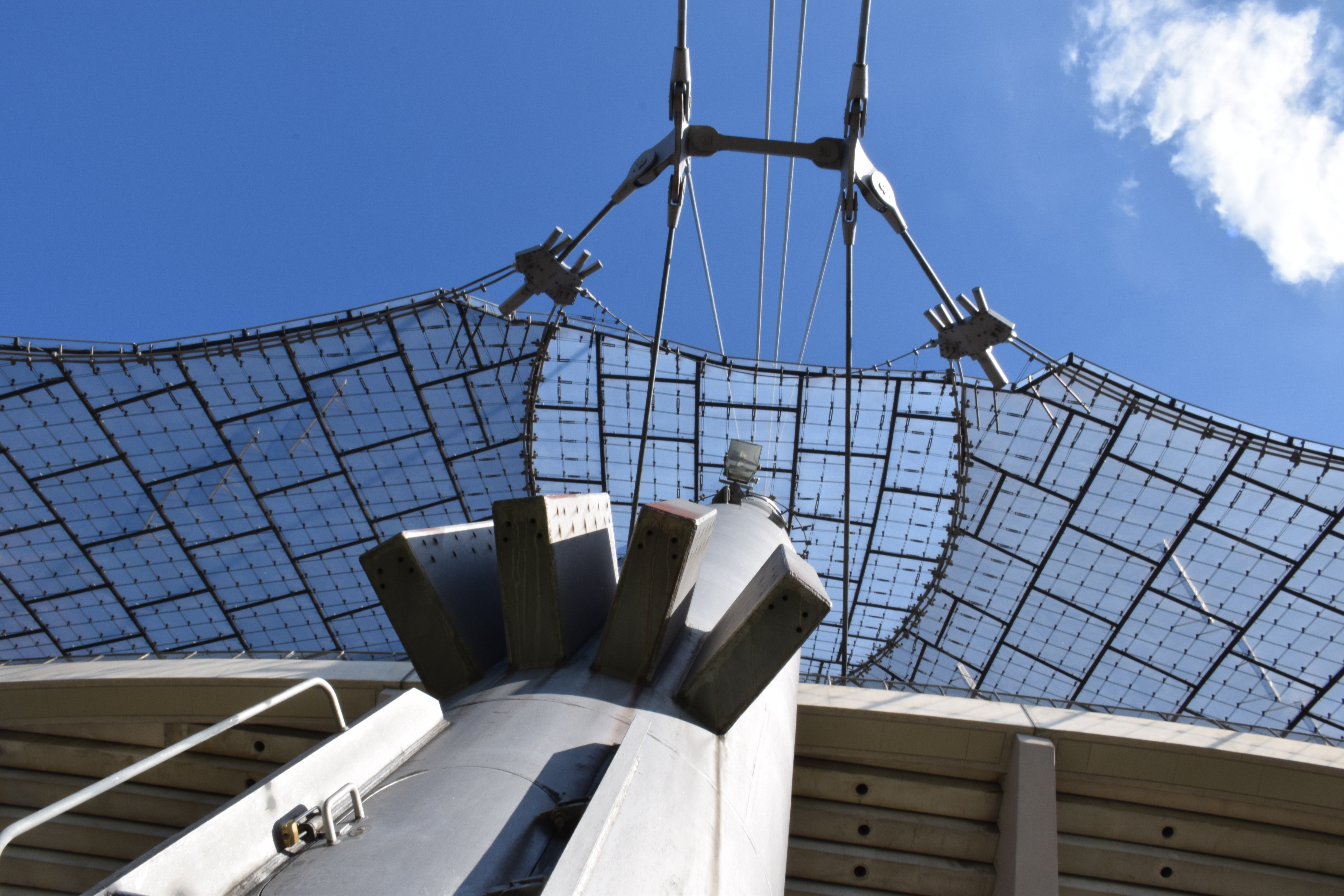 Detailní pohled na střešní konstrukci mnichovského olympijského stadionu, zobrazující inovativní závěsnou lanovou architekturu s napnutými membránami.