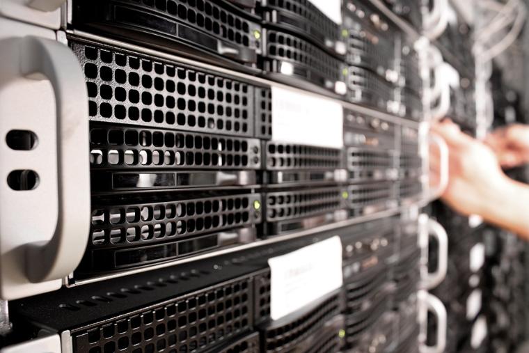 Detailní záběr serverového stojanu s několika serverovými jednotkami, které jsou chlazeny větracími mřížkami a produkují značné odpadní teplo
