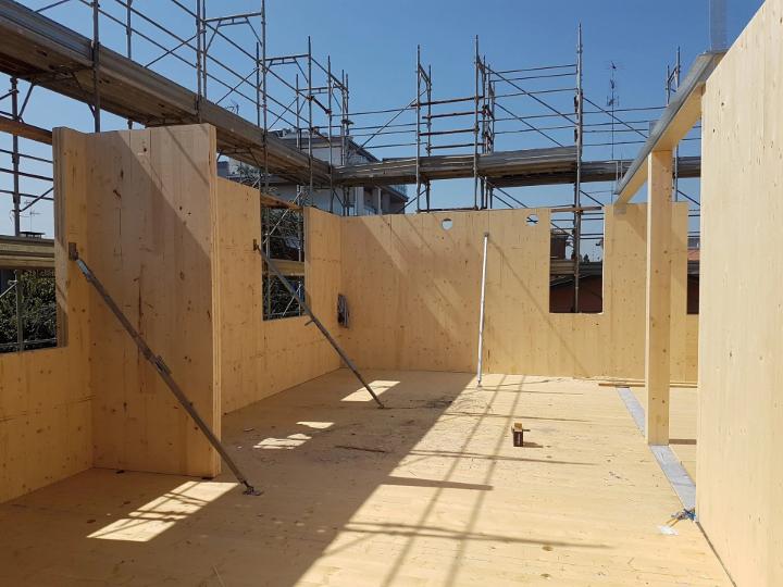 Baustelle von einem sechsgeschossigen BSP-Gebäude in Modena, Italien, mit sichtbaren Holzplatten und Konstruktion während der Montage.