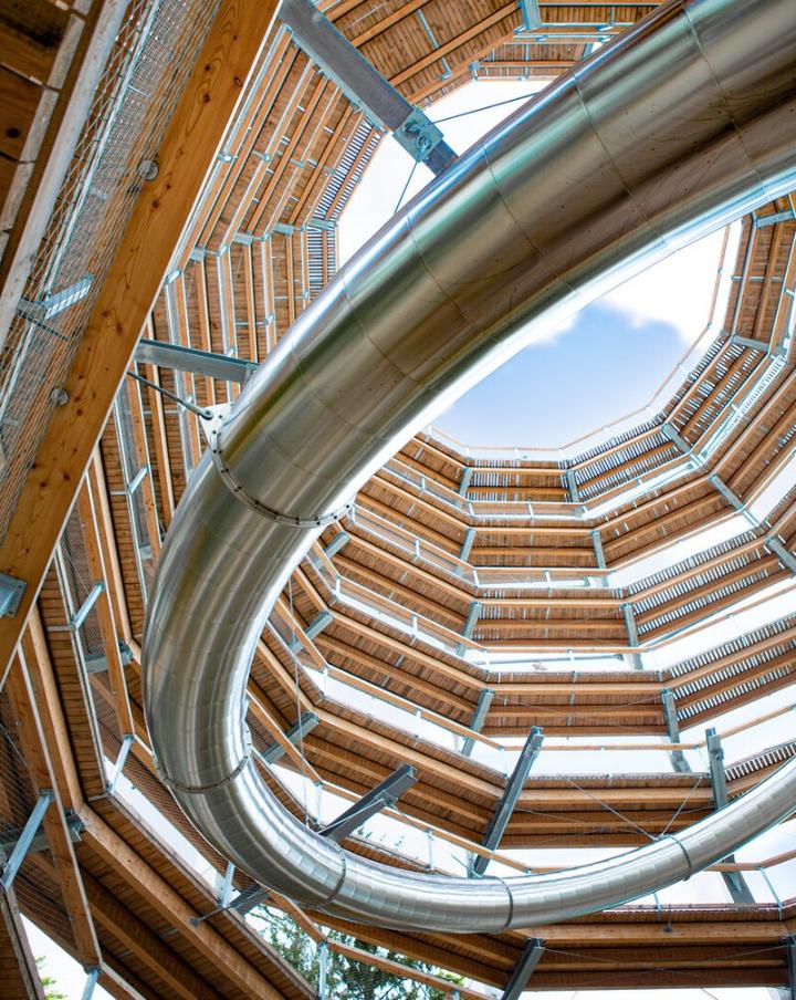 Innenansicht eines Aussichtsturms mit integrierter Tunnelrutsche, moderne Architektur.