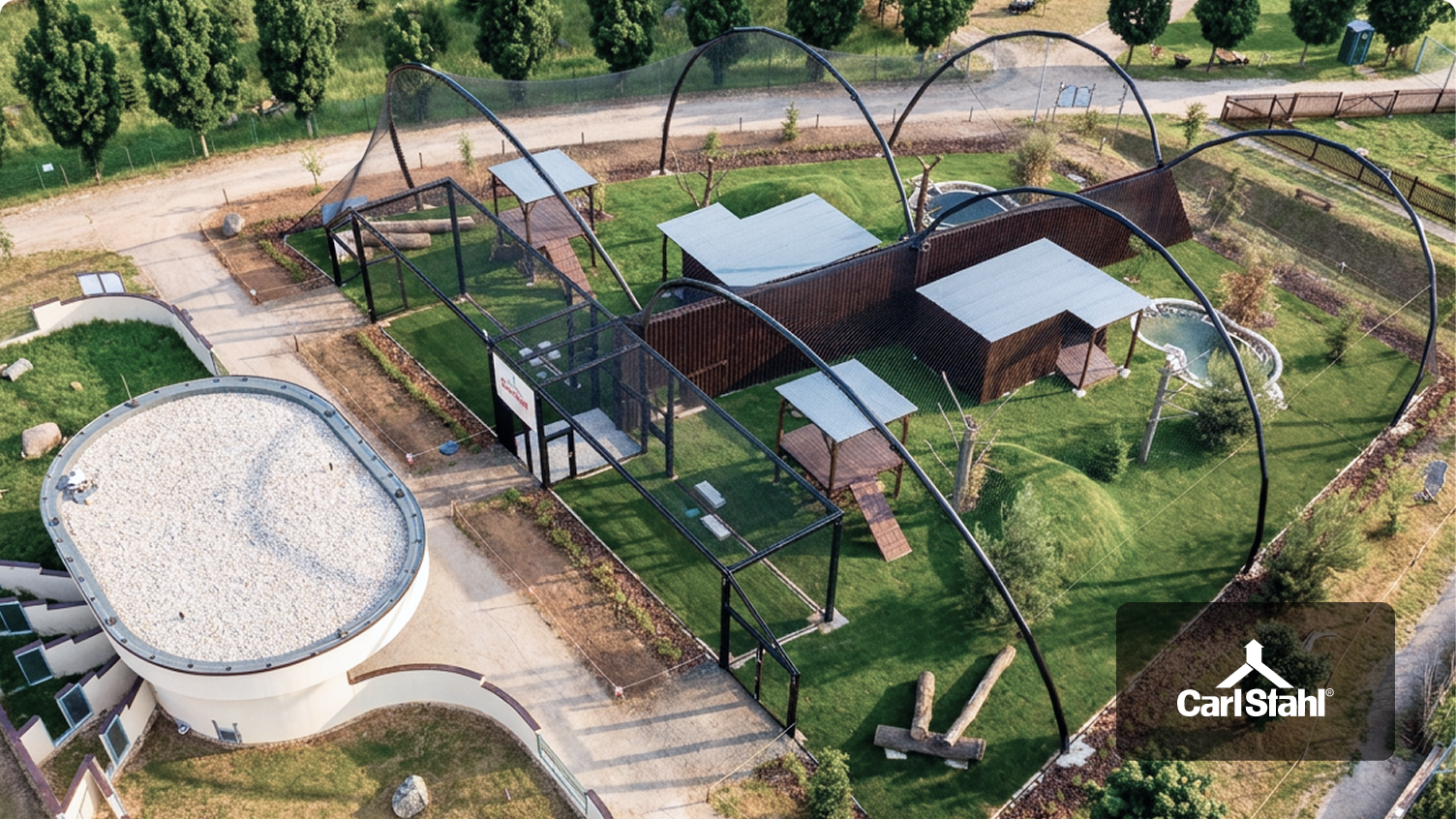 Eine Drohnenaufnahme des Pavillons des CITES-Rettungszentrums im Zoo von Tábor, die dessen moderne Stahlkonstruktionen und Edelstahlnetze zeigt.