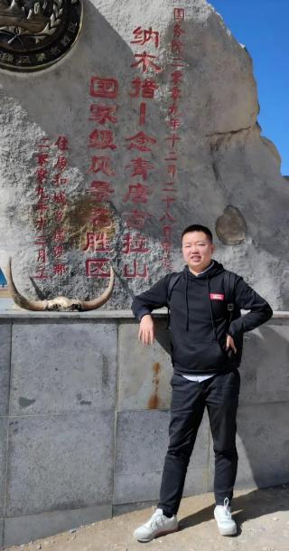 Neue Dlubal China Kollegin steht im Freien vor einem Steinmonument mit roten chinesischen Inschriften.