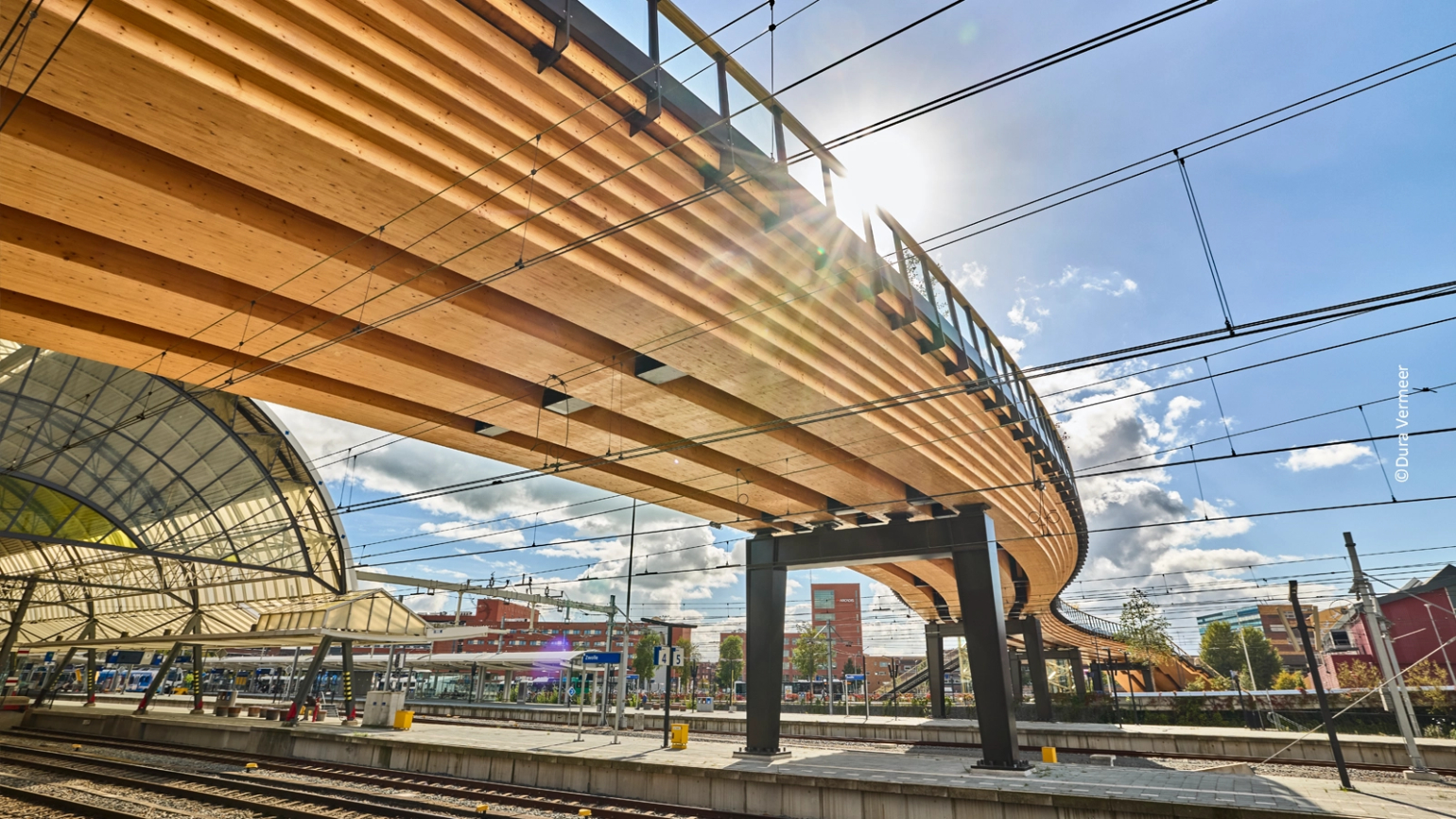 Gebogene Holzbrücke mit massiven Trägern und Stahlstützen über Bahngleisen in Zwolle, Niederlande. © Lukas Osterloff, IB Miebach.