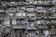 The facade of a residential building with numerous air conditioning units, which contribute to urban heat island effects because the waste heat cannot escape due to the closely spaced buildings.