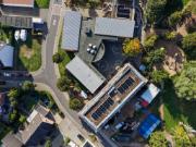 Aerial view of Otzenrath Elementary School, a hybrid-construction building featuring metal-roofed structural components, a green flat roof (still under construction), and the surrounding residential area