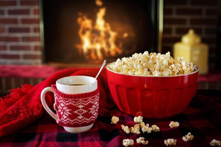 Acogedora escena de una noche de invierno con chimenea, cacao y palomitas