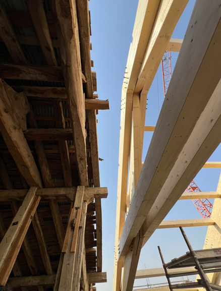 Montaje de cerchas elevadas por una grúa de gran tonelaje en sitio de construcción.