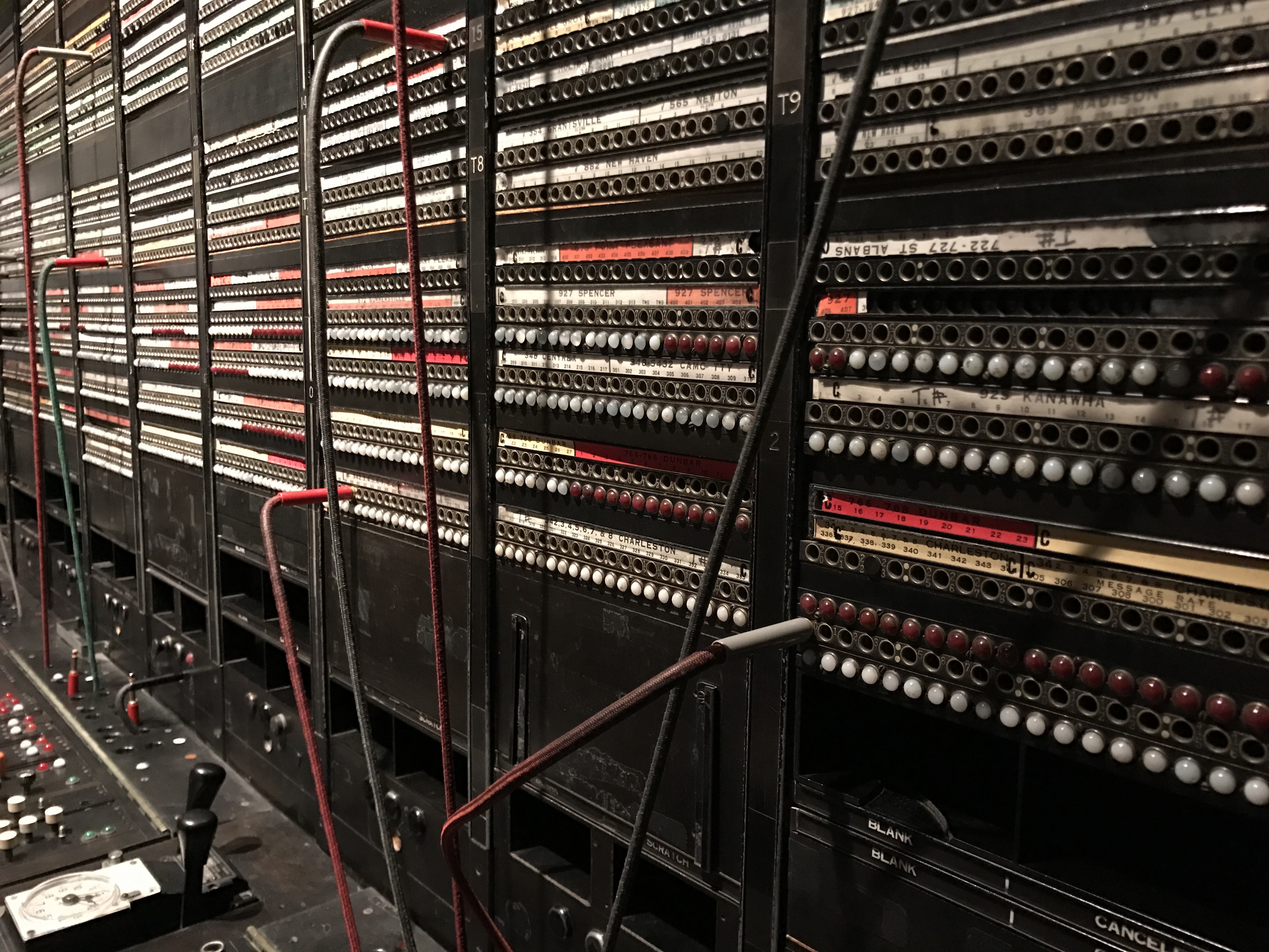 Vieille installation téléphonique avec câbles et répartiteurs dans une salle serveur. Gros plan sur une technologie obsolète.