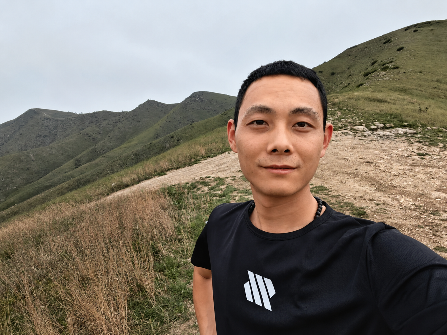 Lang Qu, nouveau membre de l'équipe commerciale de Dlubal en Chine, portant un t-shirt Dlubal dans un paysage montagneux