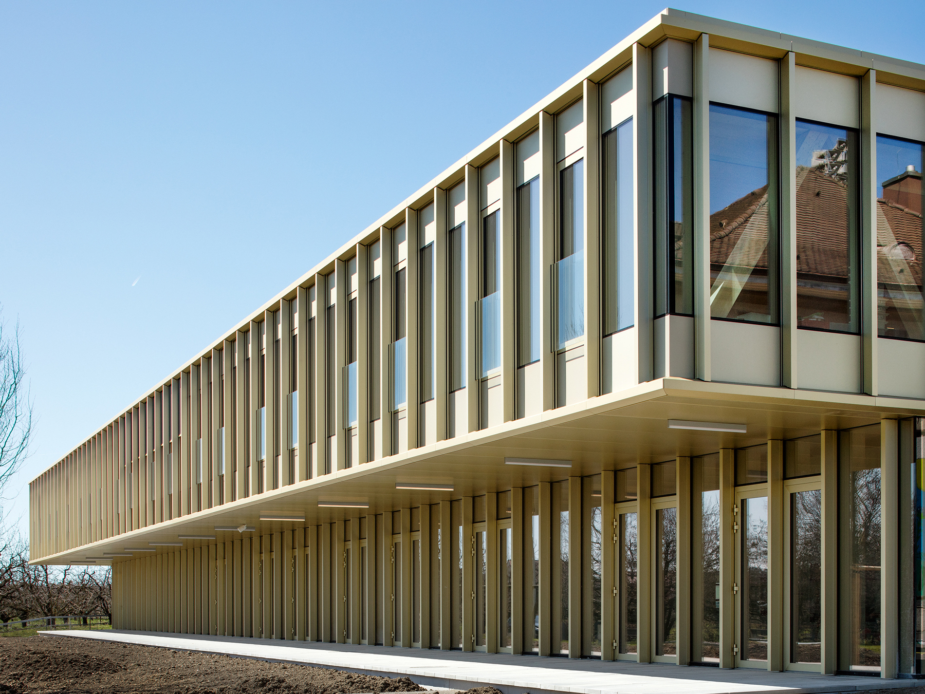 Nuovo piano superiore a sbalzo su piano terra ristrutturato dell’edificio scolastico a Sutz-Lattrigen (© Indermühle Bauingenieure)
