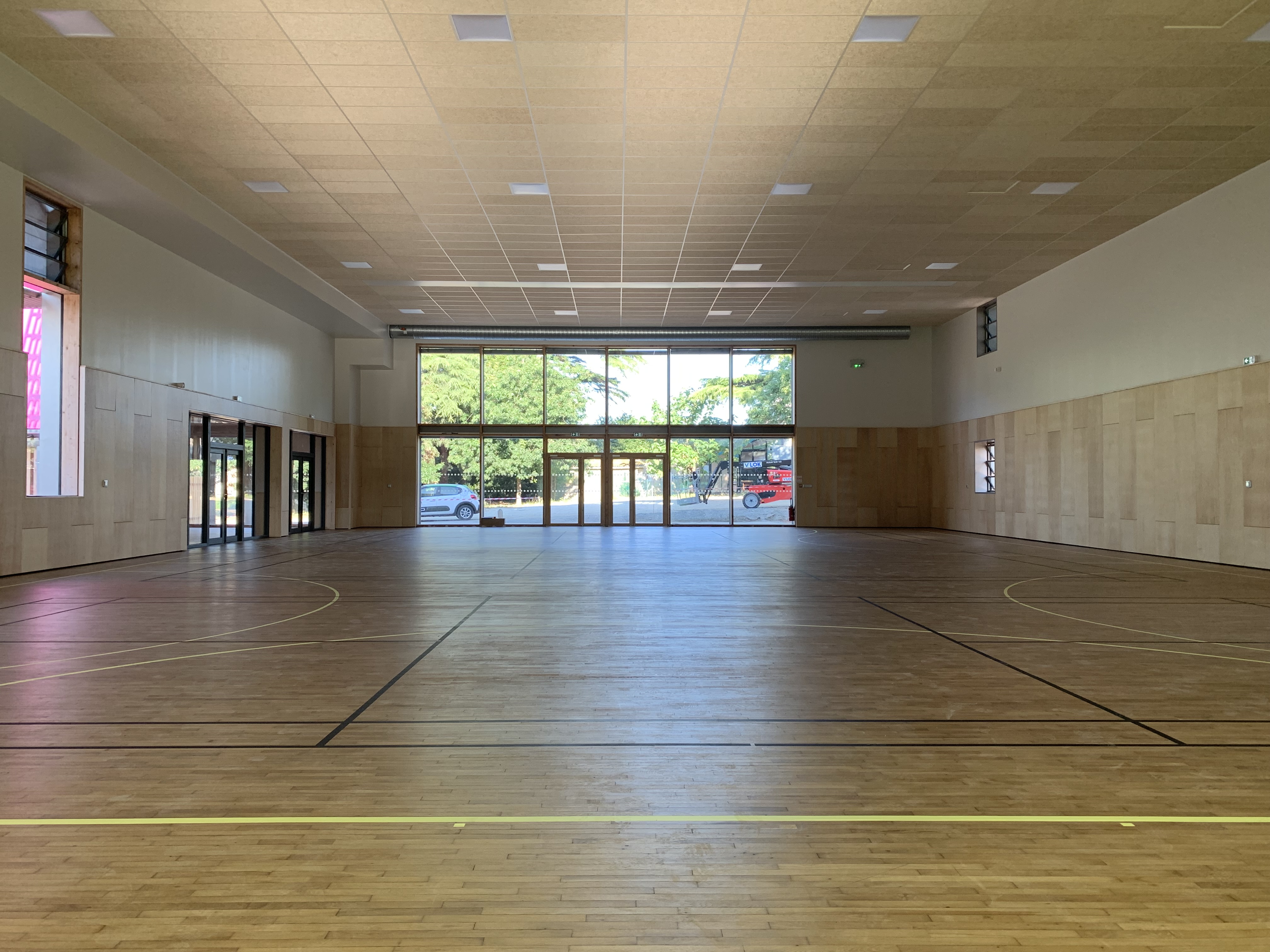 Vista interna di una palestra moderna, con elementi in legno e abbondante luce naturale.