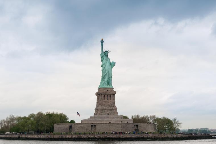 Statua della Libertà a New York con cielo azzurro sullo sfondo, simbolo di libertà e democrazia.