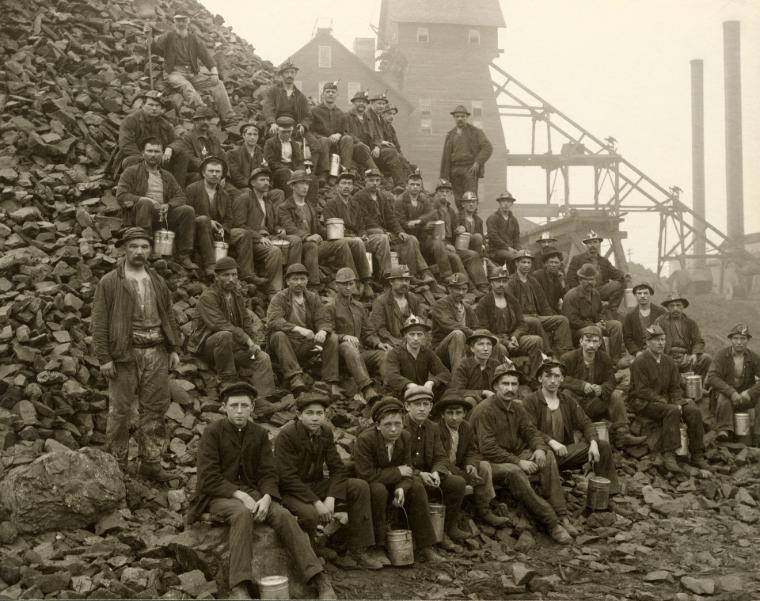 I minatori si radunano davanti a una stazione del nastro trasportatore, un’immagine classica dell’industrializzazione mineraria.