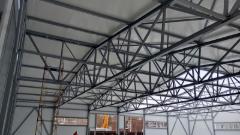 Vista dettagliata della struttura portante della copertura di un capannone con travi in acciaio e collegamenti