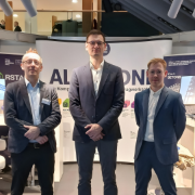 Tre dipendenti della Dlubal stanno nello stand di BIM World Munich 2025 davanti a banner su RFEM, RSTAB e altri prodotti Dlubal.