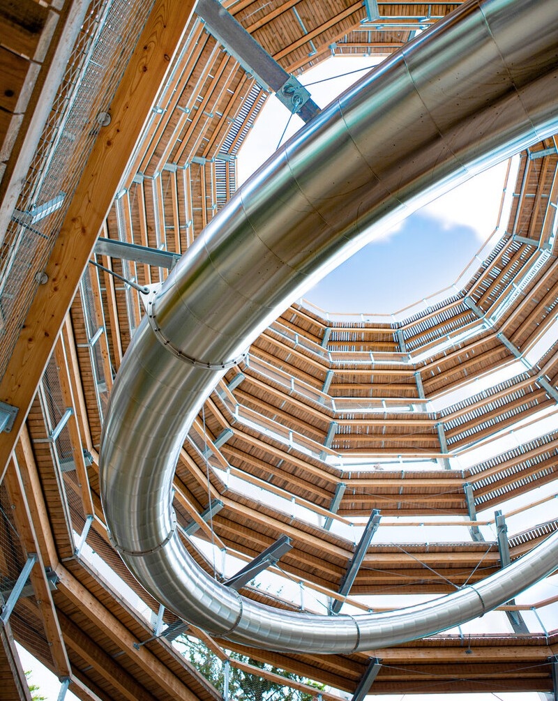Vista degli interni di una torre panoramica con scivolo a tunnel integrato, architettura moderna.