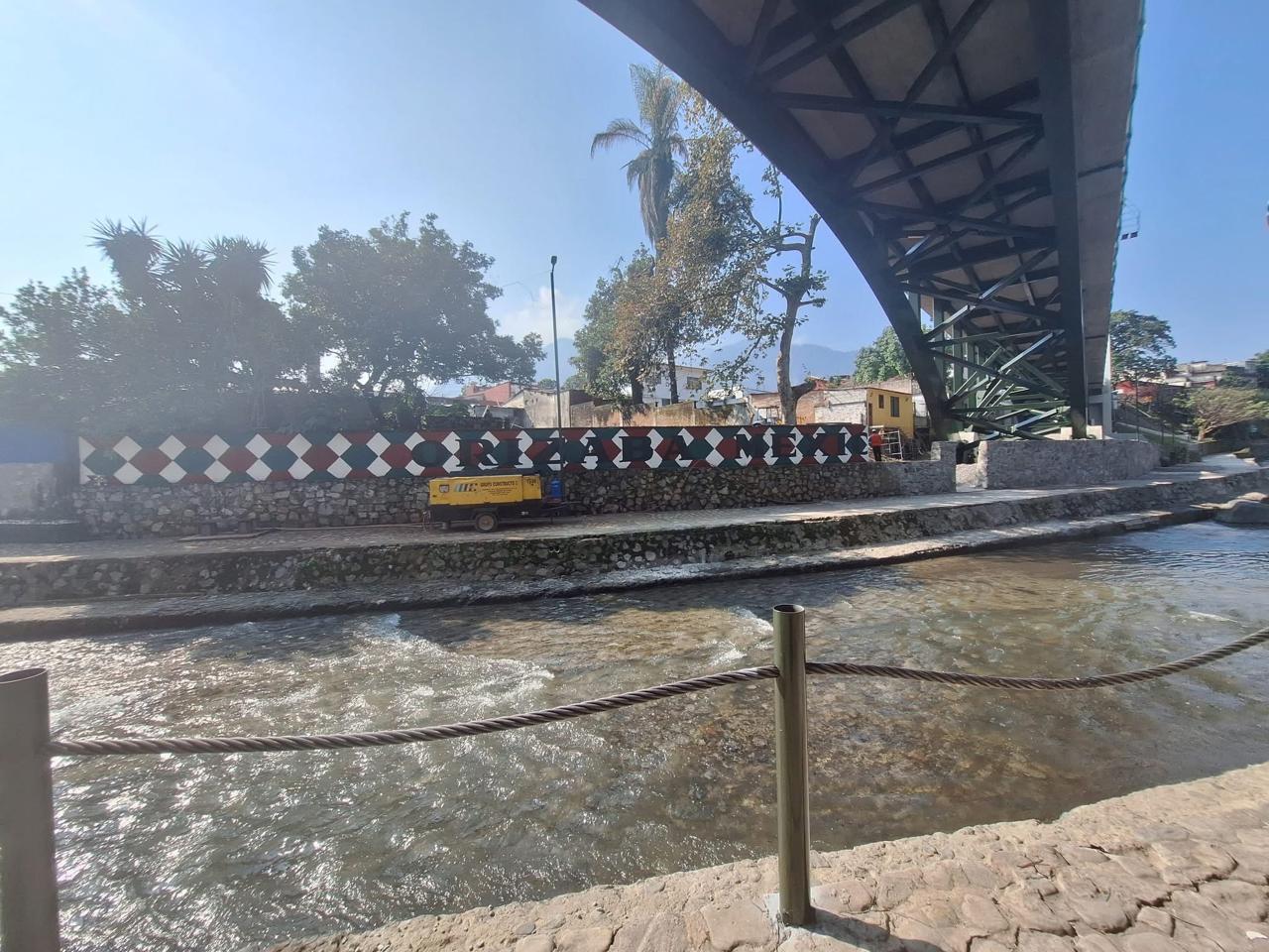 Vista inferiore di un ponte ad arco in acciaio che attraversa il fiume Orizaba a Veracruz, con muro decorato e corso d'acqua