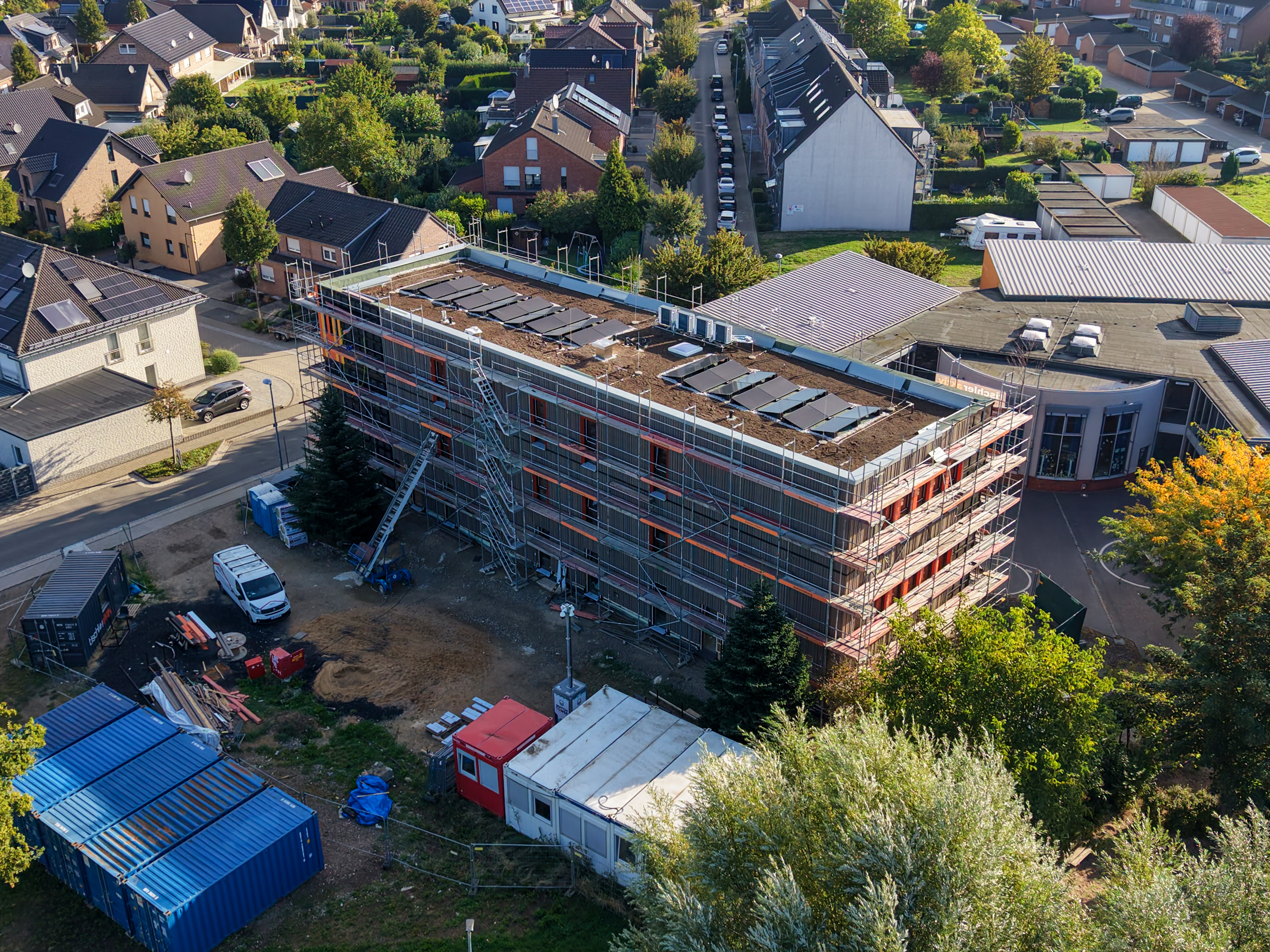 Vista aerea dell'allungamento in costruzione della scuola elementare di Otzenrath, ponteggio, tetto verde con fotovoltaico, cantiere in zona residenziale.