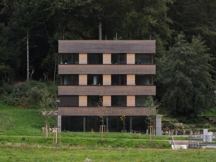 Widok od przodu leśnej wieży we Fryburgu, prosty sześcian z drewna i szkła, zintegrowany z naturą