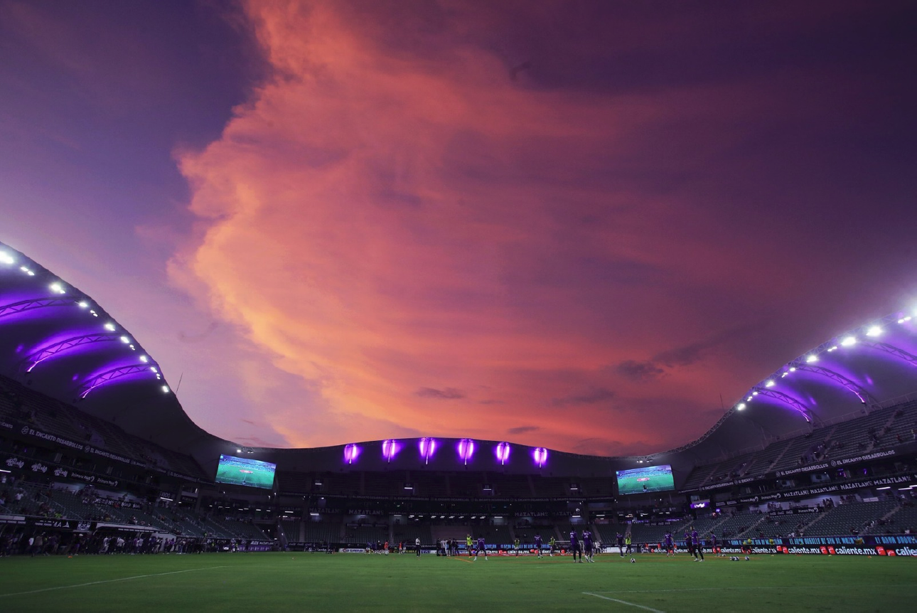 Widok na stadion Mazatlán podczas meczu, ukazujący architekturę budynku z nowoczesnymi konstrukcjami.