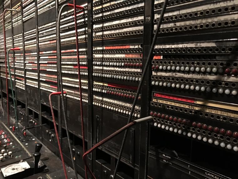 Stare centrale telefoniczne z kablami i rozdzielaczami w pomieszczeniach serwerowni. Skupienie na przestarzałej technologii.