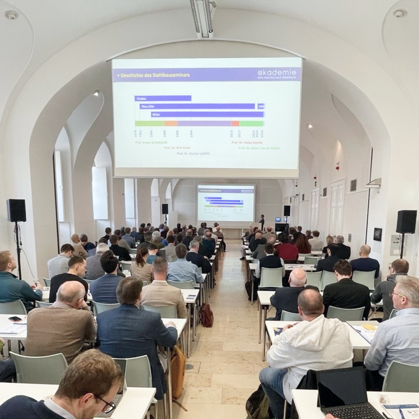 Uczestnicy omawiający tematy inżynierii konstrukcyjnej na seminarium w Wiedniu.