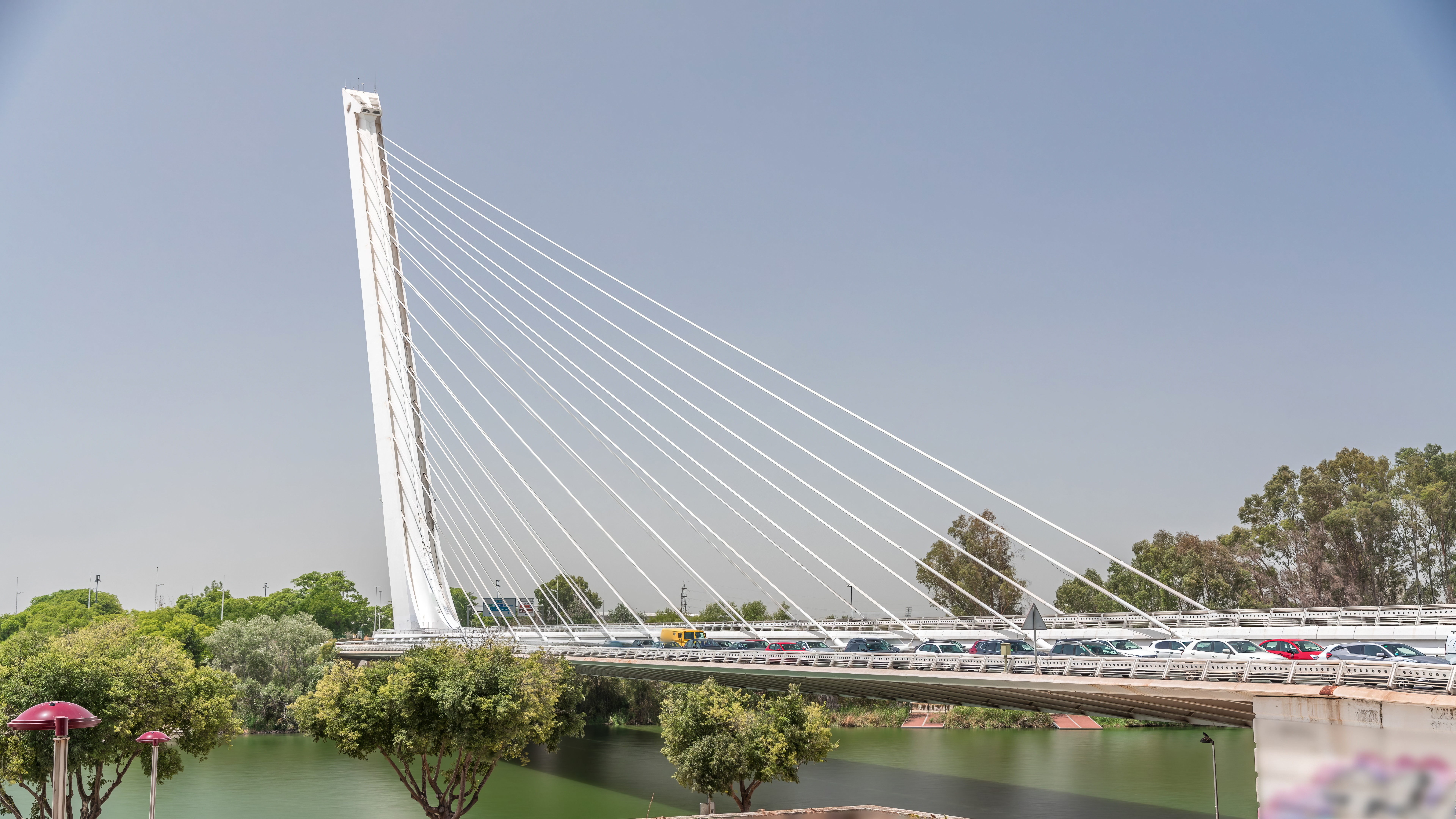 Ponte Alamillo de Santiago Calatrava apontando para o céu, cercada por água e um céu nublado.