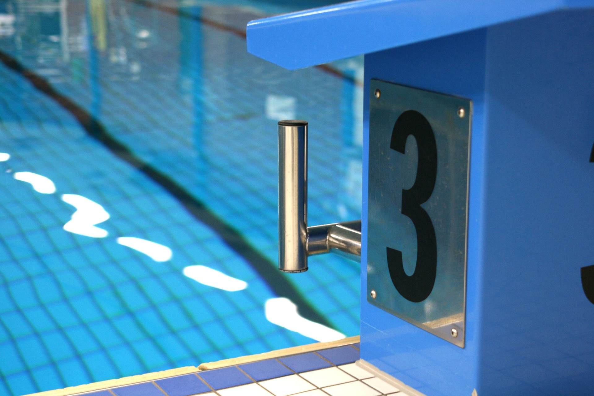 Bloco de partida no interior de uma piscina com água e marcação de pista