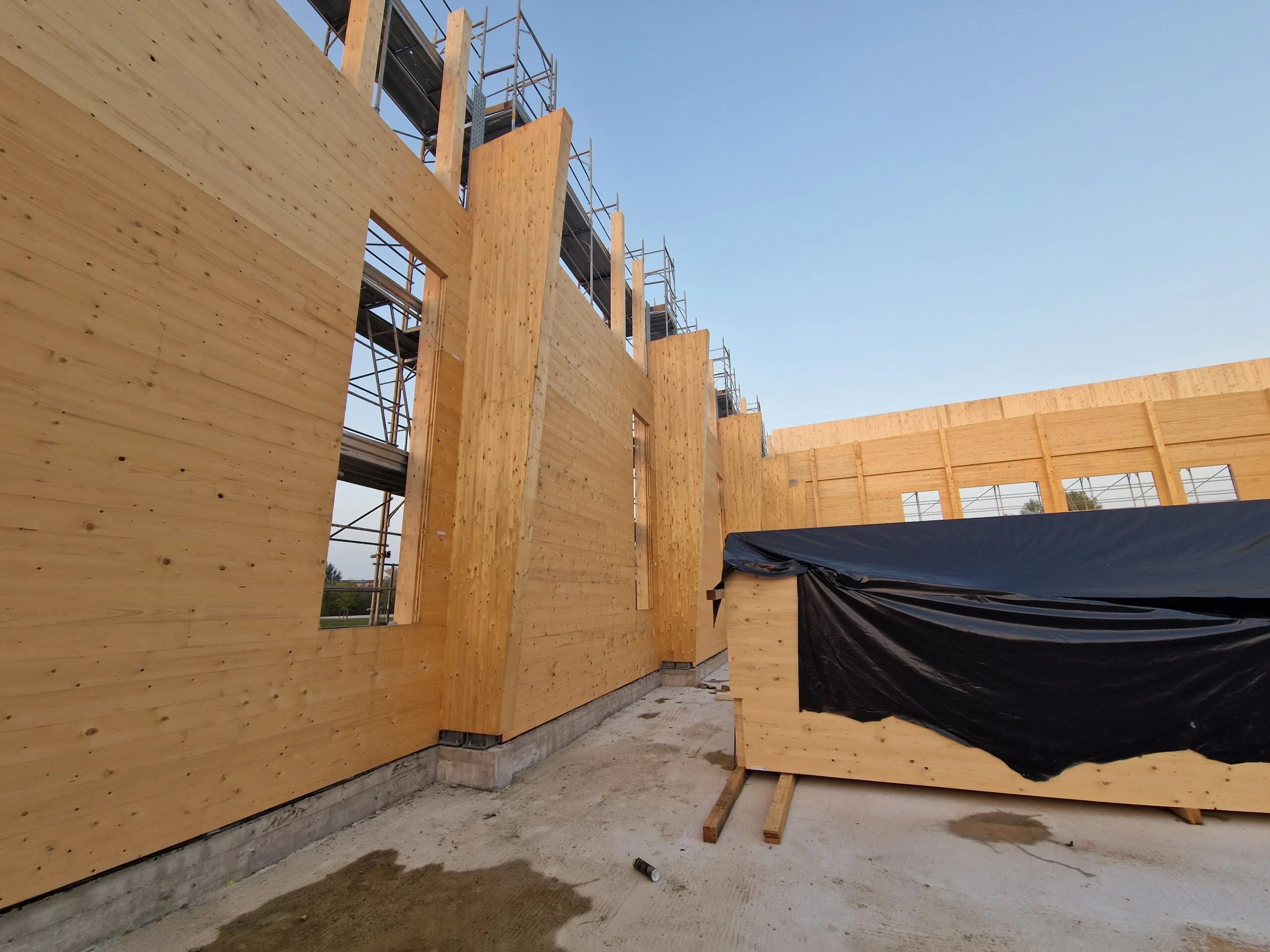 Construção do pavilhão gimnodesportivo "Corni" em Modena, Itália, destacando o progresso estrutural e o design.