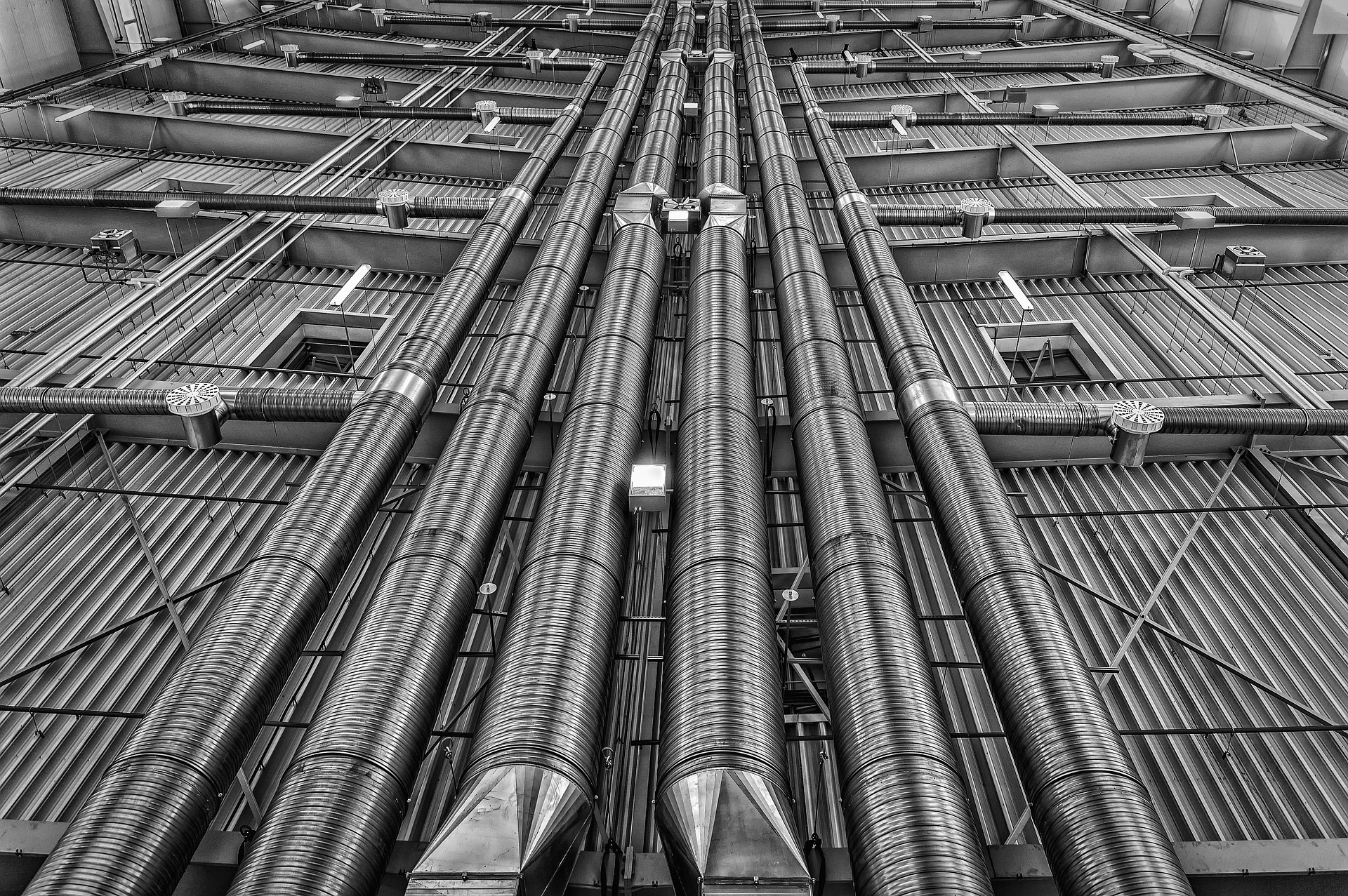 Sistema de tubos metálicos para ventilação, instalação técnica em ambiente industrial. Claramente visíveis estão os impressionantes canais estruturados.