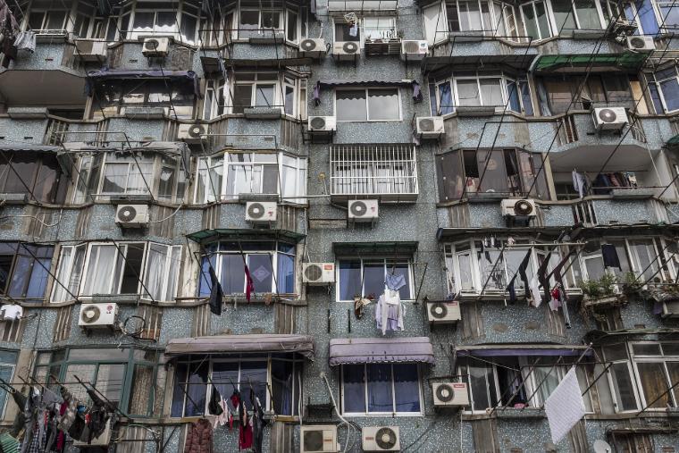 Fachada de um edifício residencial com numerosos aparelhos de ar condicionado que contribuem para o sobreaquecimento urbano, uma vez que o calor residual não pode dissipar-se devido à proximidade entre os edifícios.