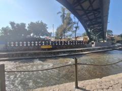 Vista inferior de uma ponte em arco de aço que cruza o rio Orizaba em Veracruz, com parede decorada e leito fluvial