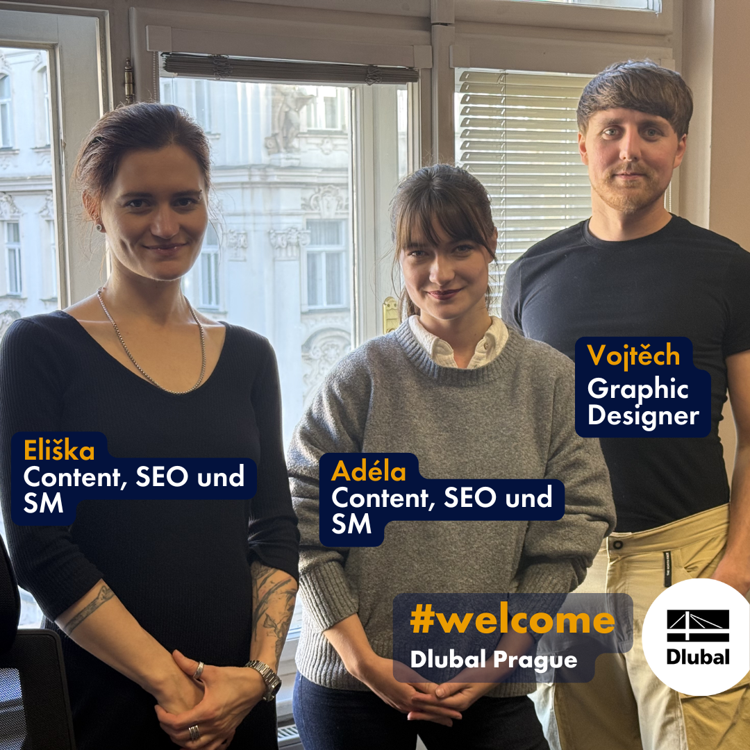 在 Dlubal 位于布拉格办公室的三名新团队成员，Eliška 和 Adéla 来自内容 SEO 社交媒体团队，Vojtěch 是平面设计师，他们站在能看到布拉格老城外墙风景的窗前。